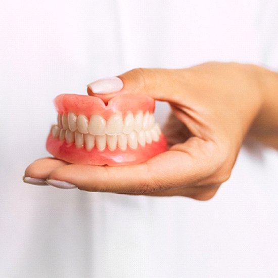 Dentist holding full dentures in Arvada