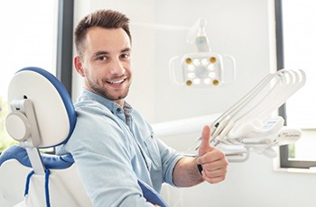 man giving a thumbs up while sitting in the dental chair 