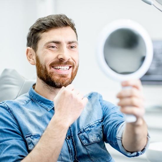 dental patient admiring smile in mirror after dental bonding in Arvada