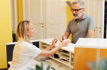 Patient and receptionist discussing how to make dentures affordable in Arvada