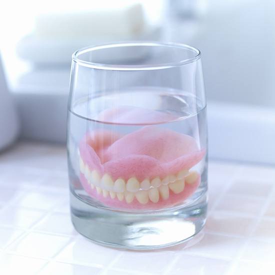 Closeup of dentures in Arvada in a glass of water