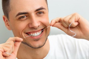 man flossing to prevent dental emergencies in Arvada