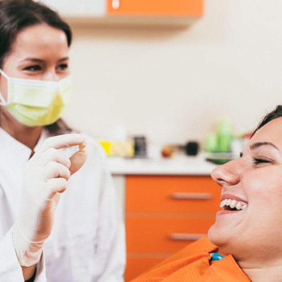 A dentist showing her patient an extracted tooth