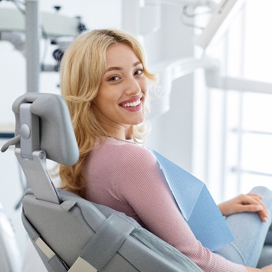 Blonde woman sitting in dental chair and smiling