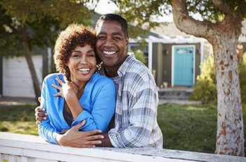 An older couple with dental implants in Arvada smiling outside