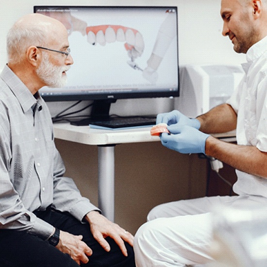 Patient learning about implant dentures in Arvada from a dentist