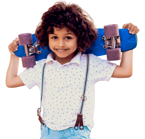 Little boy smiling and holding skateboard behind his back