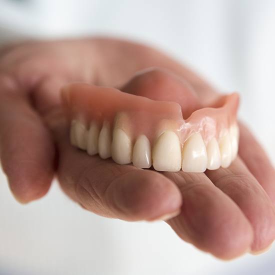 Hand holding a full denture