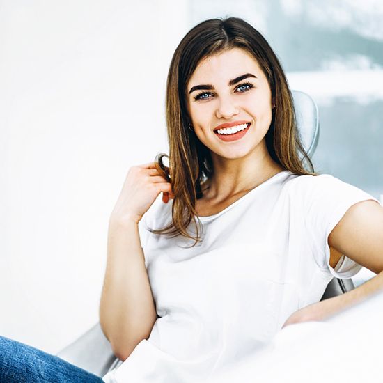 Woman leaning back and smiling after root canal therapy in Arvada, CO