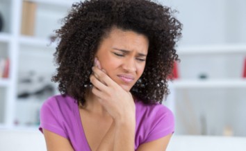 Woman in need of emergency dentistry holding jaw