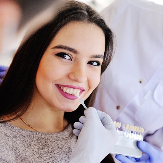 Cosmetic dentist in Arvada holding up veneer shades to patients smile
