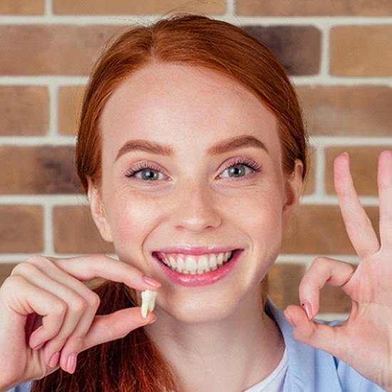 Teenage girl smiling holding tooth after wisdom tooth extraction in Arvada